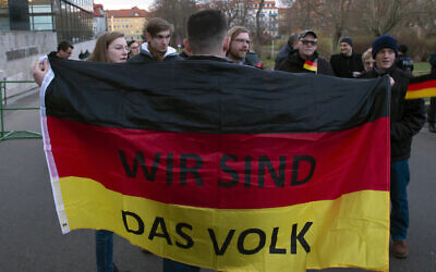 People attend a so called 'A light for democracy' silent demonstration, initiated by the far-right Alternative for Germany (AfD) party in Erfurt, central Germany, March 3, 2020. The words at the German flag read 'We are the people'. (AP Photo/Jens Meyer)