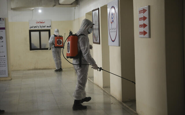 Illustrative: Members of a humanitarian aid agency disinfect Ibn Sina hospital as prevention against coronavirus in the city of Idlib, Syria, March 19, 2020. (AP Photo/Ghaith Alsayed) Illustrative: Members of a humanitarian aid agency disinfect Ibn Sina hospital as prevention against coronavirus in the city of Idlib, Syria, March 19, 2020. (AP Photo/Ghaith Alsayed)