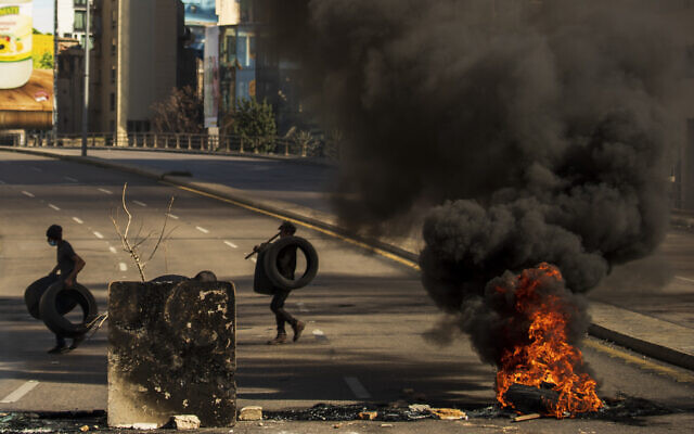 Protesters burn tires to close the main road, after the Lebanese pound hit a record low against the dollar on the black market, in Beirut, Lebanon on March 6, 2021. (AP/Hassan Ammar) Protesters burn tires to close the main road, after the Lebanese pound hit a record low against the dollar on the black market, in Beirut, Lebanon on March 6, 2021. (AP/Hassan Ammar)