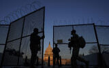 National Guard open a gate in the razor wire topped perimeter fence around the Capitol allow another member in at sunrise in Washington, March 8, 2021. (AP Photo/Carolyn Kaster)