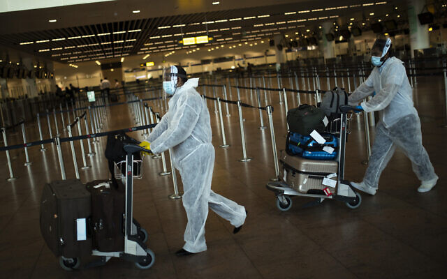 Passengers, wearing full protective gear to protect against the spread of coronavirus, push their luggage to a check-in counter at Zaventem international airport in Brussels, July 29, 2020. (AP Photo/Francisco Seco, File) Passengers, wearing full protective gear to protect against the spread of coronavirus, push their luggage to a check-in counter at Zaventem international airport in Brussels, July 29, 2020. (AP Photo/Francisco Seco, File)