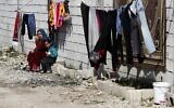 A Syrian displaced woman with her daughter sit outside their tent as they enjoy the sunny weather at a refugee camp in Bar Elias, in eastern Lebanon's Bekaa valley, Friday, March 5, 2021 (AP Photo/Hussein Malla)