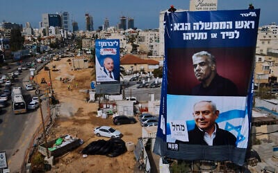 Workers hang an election campaign billboard for the Likud Party showing a portrait of its leader Prime Minister Benjamin Netanyahu, lower right, and opposition party leader Yair Lapid, upper right, next to a billboard of the Yisrael Beitenu Party showing its leader Avigdor Lieberman, in Bnei Brak, Sunday, March. 14, 2021. (AP Photo/Oded Balilty)