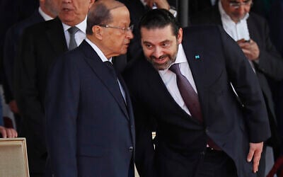 In this Nov. 22, 2018 file photo, Lebanese President Michel Aoun, left, whispers to Prime Minister Saad Hariri, during a military parade to mark the 75th anniversary of Lebanon's independence from France, in downtown Beirut, Lebanon. Lebanon's president called Wednesday, March 17, 2021 on the prime minister-designate to form a government immediately or step aside as the country plunges deeper into economic crisis. (AP Photo/Hussein Malla, File)