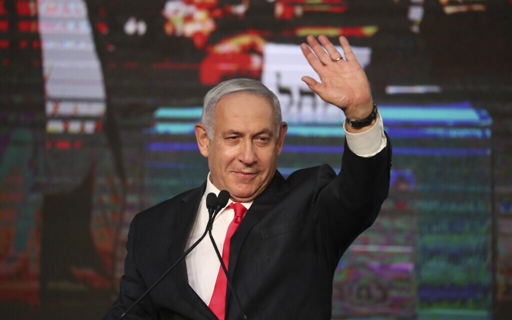 Prime Minister Benjamin Netanyahu waves to his supporters after the first exit poll results for Knesset elections at his Likud party's headquarters in Jerusalem, March 24, 2021. (AP Photo/Ariel Schalit)