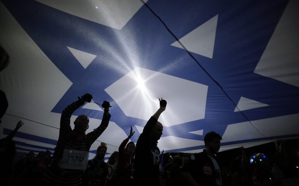 A large Israeli flag is carried during a demonstration against Prime Minister Benjamin Netanyahu In Jerusalem, Saturday, March. 20, 2021.(AP Photo/Sebastian Scheiner) A large Israeli flag is carried during a demonstration against Prime Minister Benjamin Netanyahu In Jerusalem, Saturday, March. 20, 2021.(AP Photo/Sebastian Scheiner)