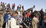 Egyptians look for remains of victims around mangled train carriages at the scene of a train accident in Sohag, Egypt, March 26, 2021. (AP Photo)