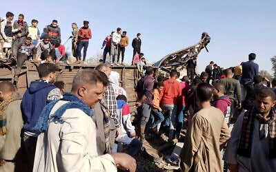 Egyptians look for remains of victims around mangled train carriages at the scene of a train accident in Sohag, Egypt, March 26, 2021. (AP Photo)
