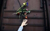 A woman places flowers on a train wagon at the old train station in Thessaloniki, Greece, on the 74th anniversary of the roundup and deportation of its Jews to Nazi extermination camps during World War II, March 19, 2017. (Giannis Papanikos/AP)