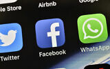 Illustrative: Icons of Facebook and WhatsApp are pictured on an iPhone. (AP/Martin Meissner)