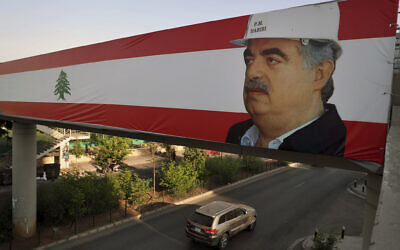 A car passes under a Lebanese flag with a picture of slain former Lebanese Prime Minister Rafik Hariri in Beirut, Lebanon, August 18, 2020. (AP Photo/Bilal Hussein)