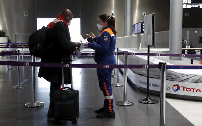 A member of Civil Protection checks air travellers documents at Paris Charles de Gaulle airport in Roissy, near Paris, February 5, 2021. (Gonzalo Fuentes/Pool via AP)