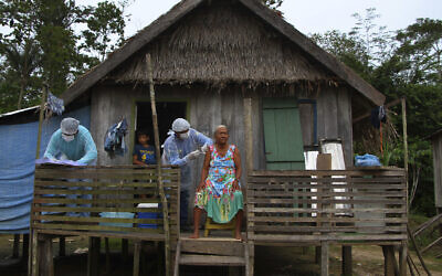 Maria Castro de Lima, 72, receives a dose of the Oxford-AstraZeneca COVID-19 vaccine from a healthcare worker, while sitting on the porch of her home in the Recanto community, along the Purus River, in the Labrea municipality, Amazonas state, Brazil,  Feb. 12, 2021. (AP Photo/Edmar Barros)