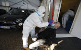 A German help worker tests for COVID-19 a French national going to Germany at the German-French border near Saarbrucken, March 2, 2021. (Jean-Francois Badias/AP)