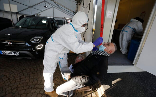 A German help worker tests for COVID-19 a French national going to Germany at the German-French border near Saarbrucken, March 2, 2021. (Jean-Francois Badias/AP) A German help worker tests for COVID-19 a French national going to Germany at the German-French border near Saarbrucken, March 2, 2021. (Jean-Francois Badias/AP)