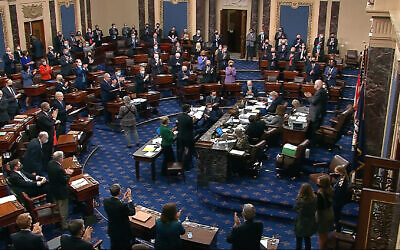 In this image from video, senators stand and applaud support staff, before the final vote on the Senate version of the COVID-19 relief bill in the Senate at the US Capitol in Washington, March 6, 2021. (Senate Television via AP)