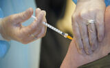 A health worker administers a dose of the AstraZeneca vaccine against COVID-19 to a patient inside the convention center known as "La Nuvola", The Cloud, in Rome, Wednesday, March 10, 2021. (AP/Andrew Medichini)