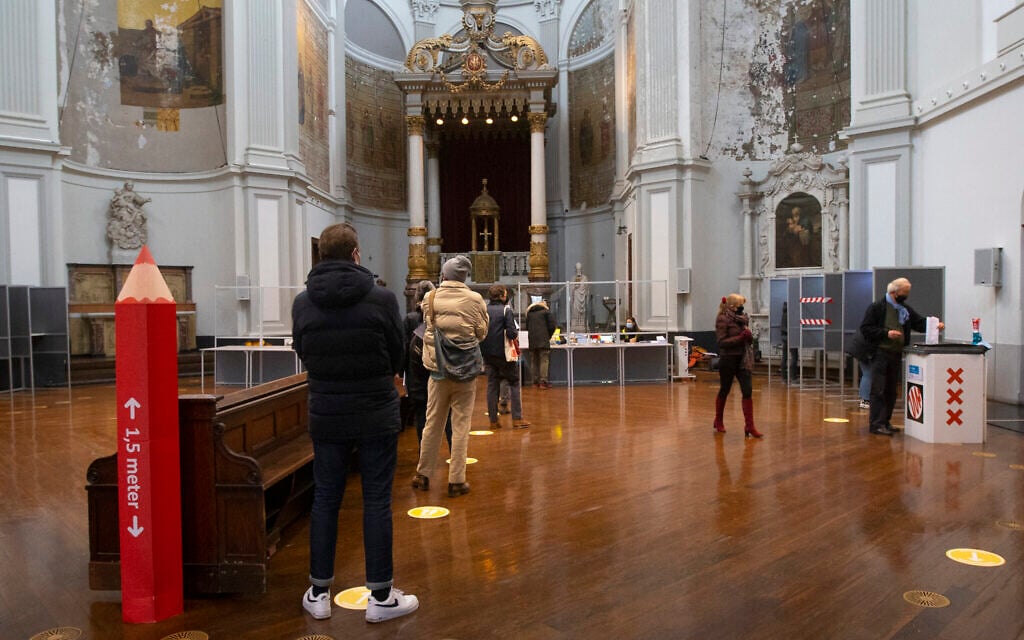 A red voting pencil reminds people queueing to cast their ballots to respect the 1.5-meter social distance at a polling station in church De Duif in Amsterdam, Netherlands, March 15, 2021. (AP Photo/Peter Dejong)