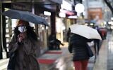 A woman wearing a mask to protect against the spread of coronavirus walks in the rain, in Ankara, Turkey, Tuesday, March 16, 2021 (AP Photo/Burhan Ozbilici)