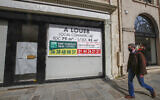 A man wearing a mask to prevent the spread of the coronavirus walks past a vacant boutique for rent in Paris,  March 25, 2021 (AP Photo/Michel Euler)