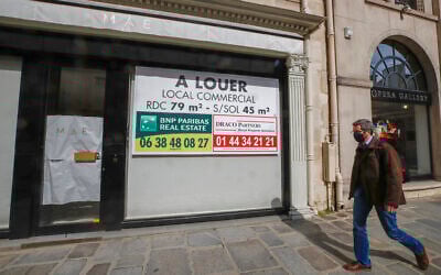 A man wearing a mask to prevent the spread of the coronavirus walks past a vacant boutique for rent in Paris,  March 25, 2021 (AP Photo/Michel Euler)