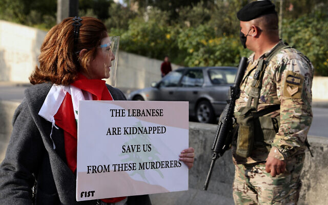 An anti-government protester holds a placard, as she looks at a Lebanese army soldier, during a protest against the political leadership they blame for the economic and financial crisis, near the presidential palace in Baabda, east of Beirut, Lebanon, March. 27, 2021. (Bilal Hussein/AP) An anti-government protester holds a placard, as she looks at a Lebanese army soldier, during a protest against the political leadership they blame for the economic and financial crisis, near the presidential palace in Baabda, east of Beirut, Lebanon, March. 27, 2021. (Bilal Hussein/AP)
