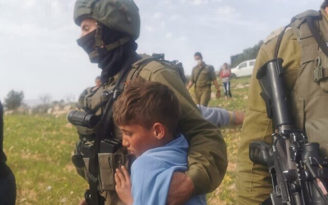 IDF soldiers arrest Palestinian children picking spices in a West Bank field on March 10, 2021. (B'Tselem) IDF soldiers arrest Palestinian children picking spices in a West Bank field on March 10, 2021. (B'Tselem)