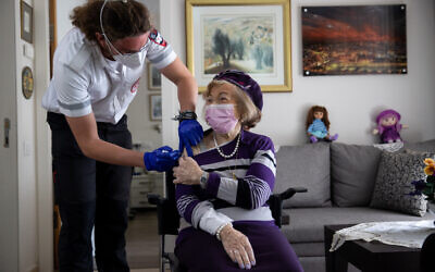 Illustrative: A Magen David Adom worker administers a COVID-19 vaccine to Holocaust survivor Yaffa Balaban, 95, at her apartment in Beit Tovei Hair retirement residence in Jerusalem on January 26, 2021. (Yonatan Sindel/Flash90)
