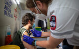 An Israeli man receives a COVID-19 vaccine shot at a mobile Magen David Adom vaccination station at the Mahane Yehuda market in Jerusalem on February 22, 2021. (Olivier Fitoussi/Flash90)