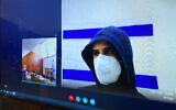 Yarin Sherf, suspected of raping 13-year-old girl at a quarantine hotel, is seen on a screen via a video link during a court hearing at the Tel Aviv Magistrate's Court, March 1, 2021. (Avshalom Sassoni/Flash90)