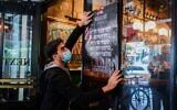 A worker at a restaurant in Tel Aviv hangs a 'help wanted' sign on the window, on March 3, 2021. (Avshalom Sassoni/Flash90)