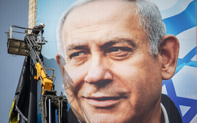 Israeli workers put up a giant election campaign poster showing Prime Minister Benjamin Netanyahu of the Likud party, in Jerusalem on March 10, 2021. (Yonatan Sindel/Flash90)