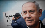 A man walks near an election campaign poster showing Prime Minister Benjamin Netanyahu in Jerusalem on March 18, 2021 (Yonatan Sindel/Flash90)