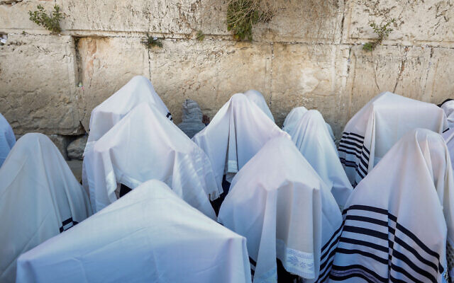 File: Jewish worshippers cover themselves with prayer shawls as they pray in front of the Western Wall, during the priestly blessing event of the Passover holiday, March 29, 2021. (Olivier Fitoussi/Flash90)