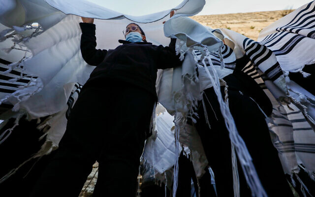 Jewish worshippers cover themselves with prayer shawls as they pray in front of the Western Wall, during the priestly blessing event of the Passover holiday, March 29, 2021. (Olivier Fitoussi/Flash90)