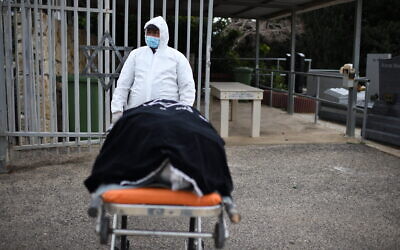 Illustrative image: A burial services employee with the remains of  a coronavirus victim on January 28, 2021. (Gili Yaari / Flash90)