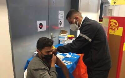 Ahmad Atwan, a Palestinian from a town near Hebron, receives the first dose of a coronavirus vaccine by Magen David Adom during an Israeli campaign to immunize Palestinians who work in Israel (Aaron Boxerman/The Times of Israel)