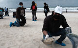 Israelis clean tar off the Bat Yam beach following an offshore oil spill which polluted most of the Israeli coastline, March 2, 2021. (Tomer Neuberg/Flash90)
