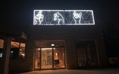 The neon hands spelling out the word 'light' in Hebrew and Arabic sign language at the new home of the Mekudeshet cultural organization in Jerusalem, opened during the coronavirus pandemic (Jessica Steinberg/Times of Israel)