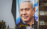 Israeli workers hang large election campaign posters of the Likud party, as part of the Likud election campaign, in Jerusalem on March 10, 2021. (Yonatan Sindel/Flash90)