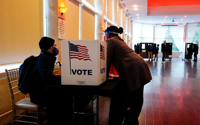In this Nov. 3, 2020, file photo, a poll worker talks to a voter before they vote on a paper ballot on Election Day in Atlanta, Georgia. (AP Photo/Brynn Anderson, File) In this Nov. 3, 2020, file photo, a poll worker talks to a voter before they vote on a paper ballot on Election Day in Atlanta, Georgia. (AP Photo/Brynn Anderson, File)