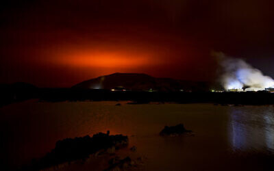 The red shimmer from magma flowing out from the erupting Fagradalsfjall volcano behind the landmark Blue Lagoon, some 45 km west of the Icelandic capital Reykjavik, on March 19, 2021. (Halldor KOLBEINS / AFP)
