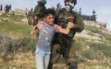 An Israeli soldier detains a Palestinian child close to al-Rakiz in the south Hebron hills on Wednesday, March 10, 2021 (Credit: Nasr Nawajaa/B'Tselem)