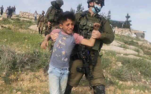 An Israeli soldier detains a Palestinian child close to al-Rakiz in the south Hebron hills on Wednesday, March 10, 2021 (Credit: Nasr Nawajaa/B'Tselem) An Israeli soldier detains a Palestinian child close to al-Rakiz in the south Hebron hills on Wednesday, March 10, 2021 (Credit: Nasr Nawajaa/B'Tselem)
