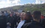 MK Mansour Abbas (c) is led away by security guards after being heckled and accosted at a protest in Umm el-Fahm on March 5, 2021.(Screencapture/Twitter)