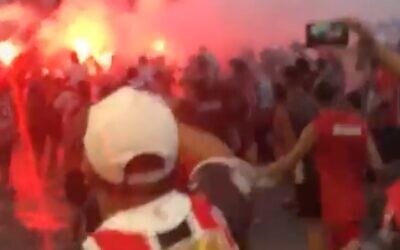 A screenshot from the viral video of Chacarita fans chanting an anti-Semitic line shows them marching near a bonfire on the street. (via JTA)