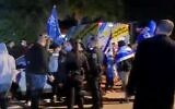 Supporters of Prime Minister Benjamin Netanyahu are watched by police officers outside an event for Gideon Sa'ar's New Hope party, March 13, 2020 Screen grab/Channel 13)