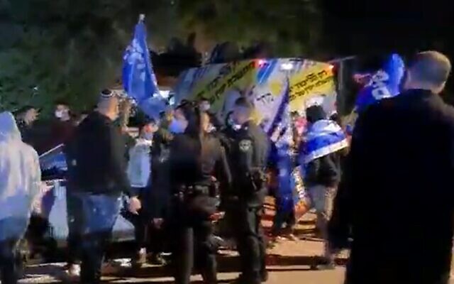 Supporters of Prime Minister Benjamin Netanyahu are watched by police officers outside an event for Gideon Sa'ar's New Hope party, March 13, 2020 Screen grab/Channel 13) Supporters of Prime Minister Benjamin Netanyahu are watched by police officers outside an event for Gideon Sa'ar's New Hope party, March 13, 2020 Screen grab/Channel 13)