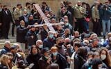 Christian worshippers carrying a wooden cross arrive at the Church of the Holy Sepulchre, during a Good Friday procession along the Via Dolorosa (Way of Suffering) in Jerusalem's Old City on April 2, 2021. (Emmanuel DUNAND / AFP)