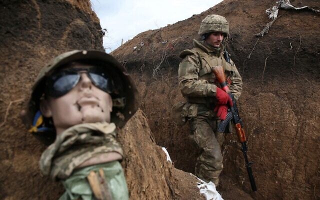 A Ukrainian serviceman walks in a trench by a mannequin as he stands at his post on the frontline with Russia-backed separatists near the town of Zolote, in the Lugansk region on April 8, 2021 (STR / AFP)